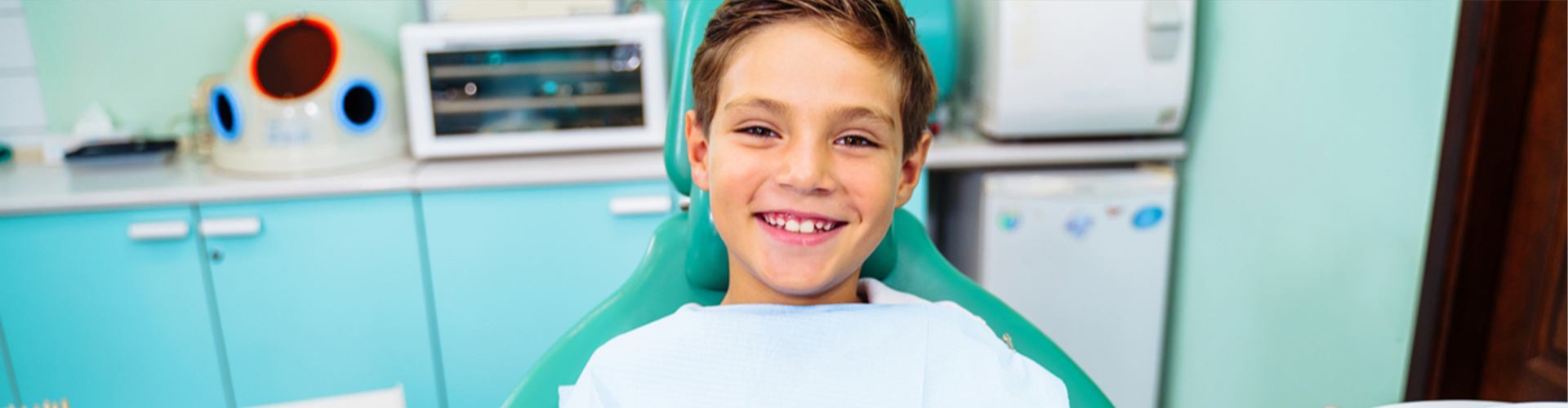 kid smiling in dentist chair giving two thumbs up