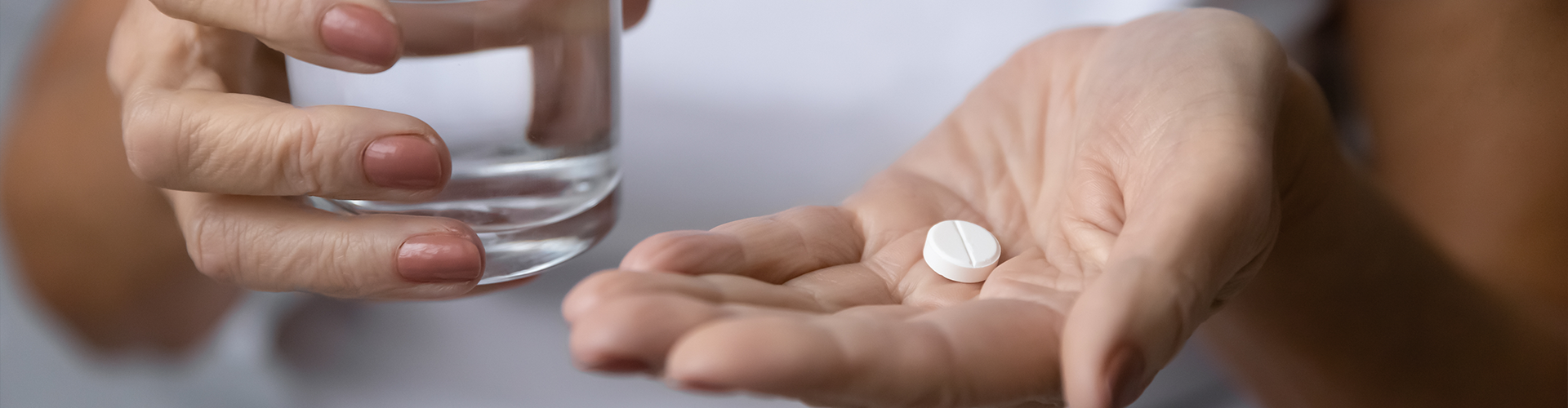 hands holding a pill tablet and a glass of water