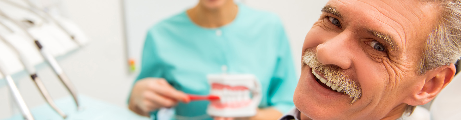 man smiling while dentist holds mouth model