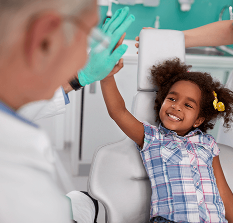 A dentist giving a high five to a child patient.