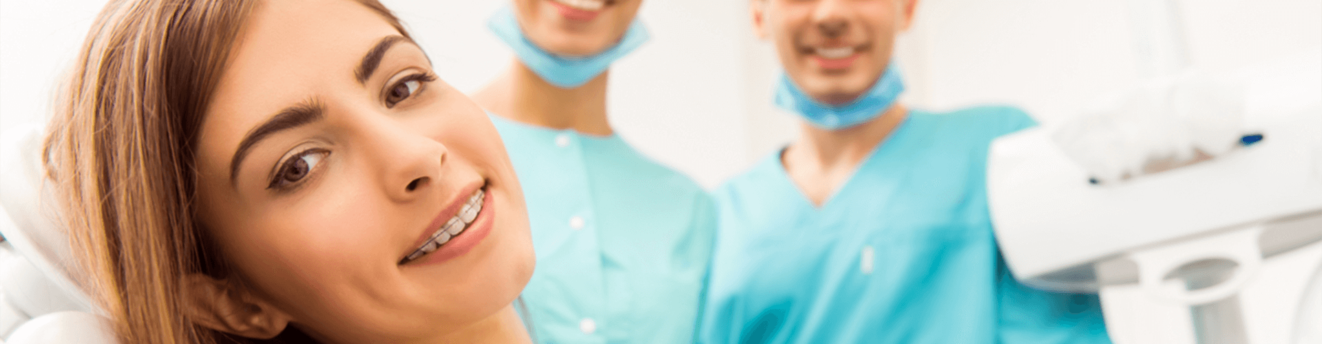 girl with braces smiling in front of dental staff