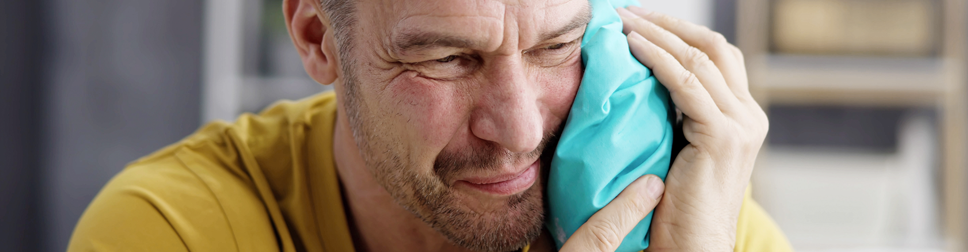 man holding ice pack on cheek