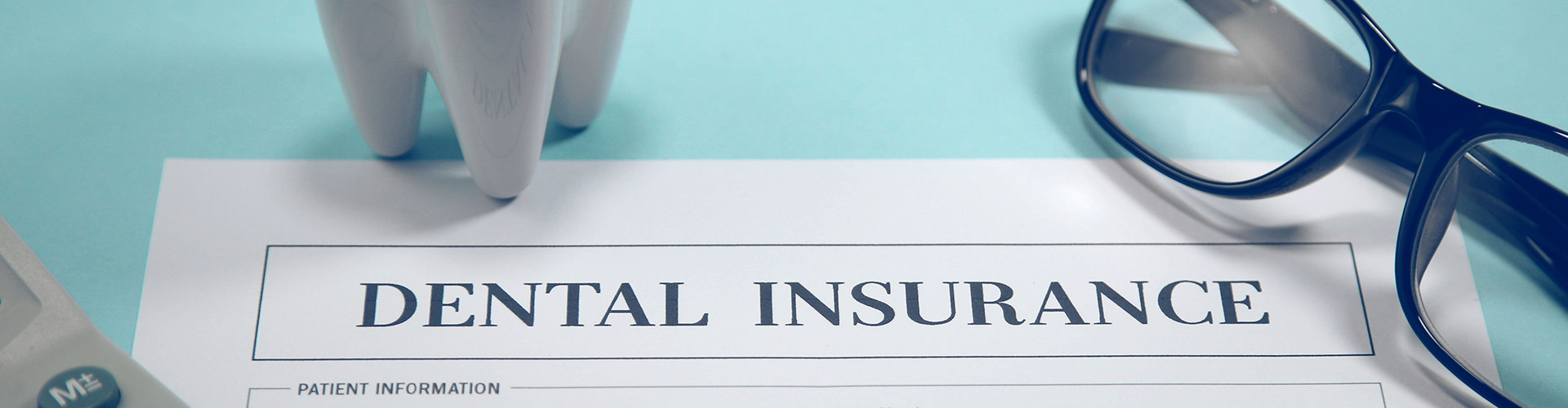 dental insurance form and glasses beside a tooth model