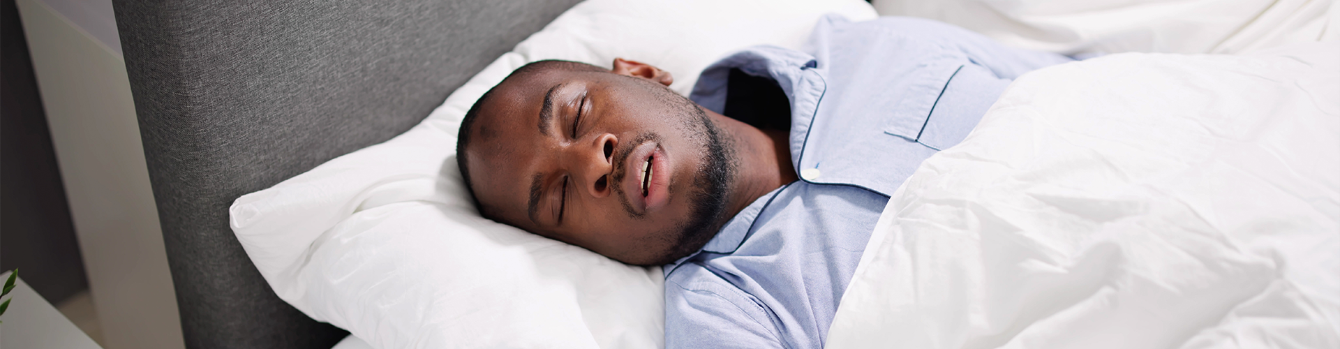 man sleeping on his back in bed