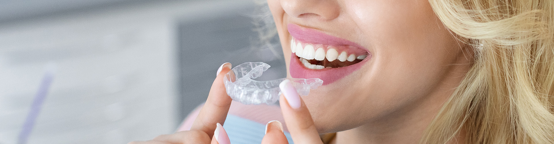 smiling woman holding clear aligner