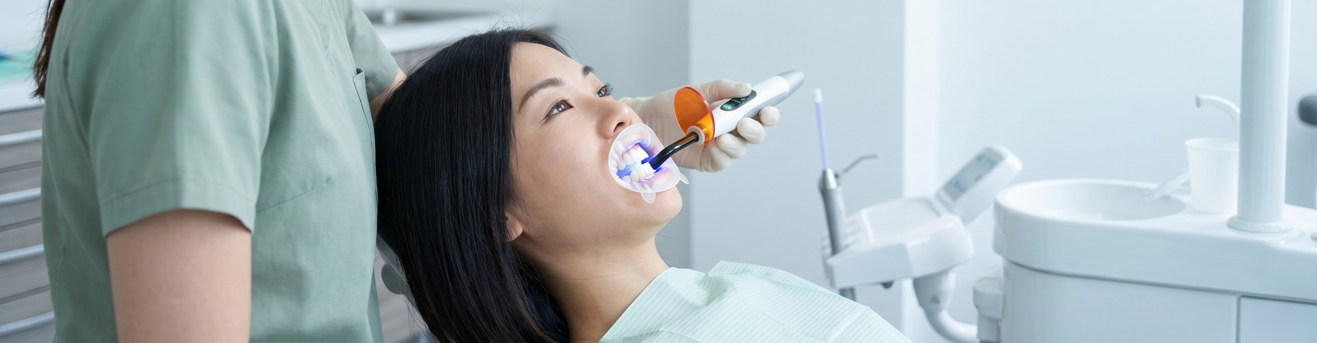 Dental-professional-shining-teeth-whitening-light-on-female-patient's-teeth.