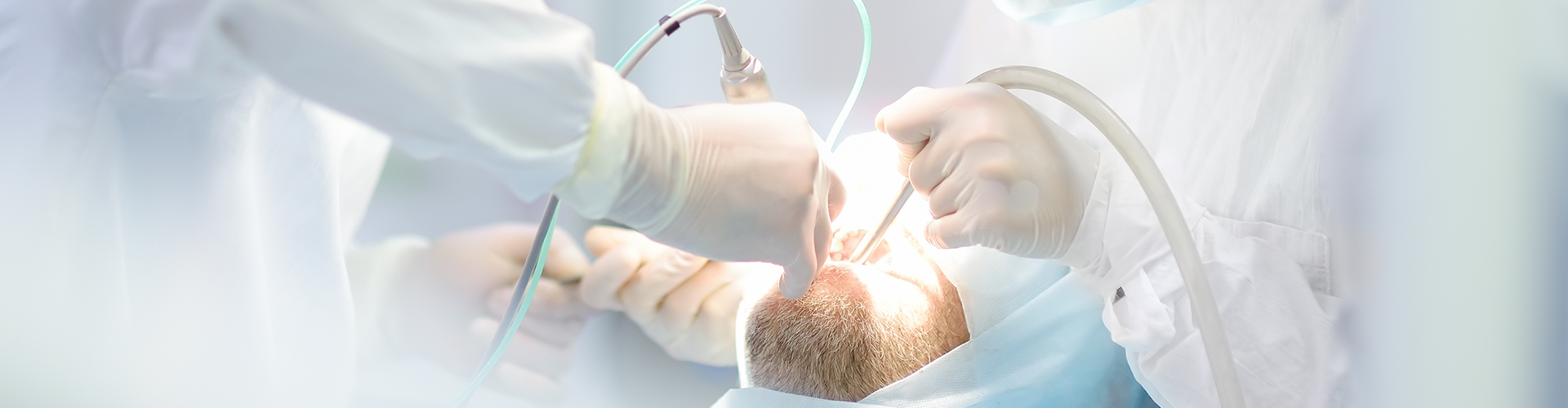 three dental professionsals performing procedures in patient's mouth
