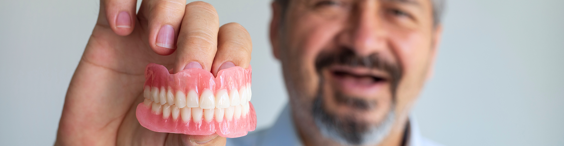toothless man holding a pair of dentures