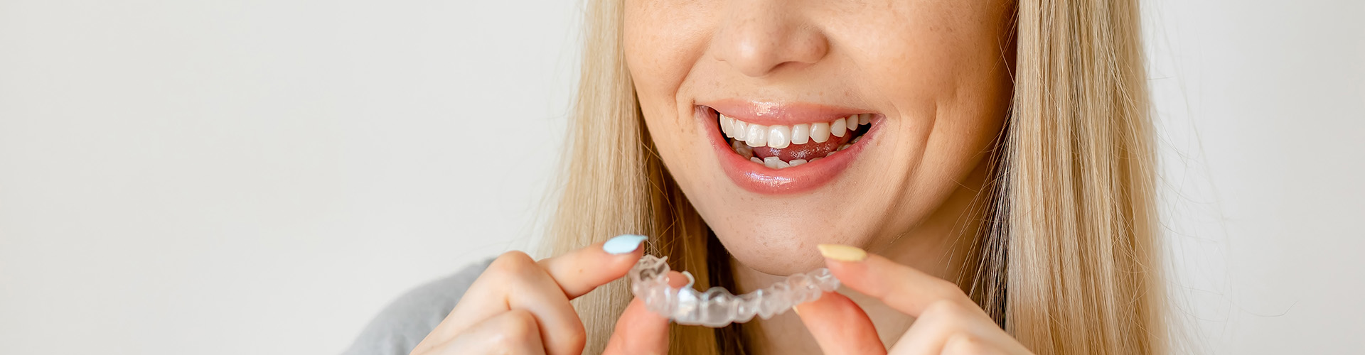 smiling woman holding clear aligner