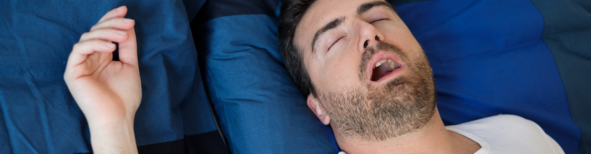 man on his back snoring in bed