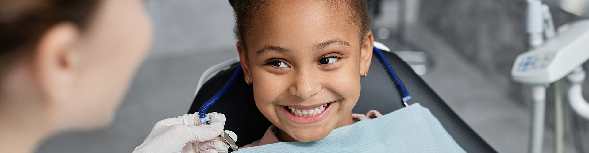 child in dental chair smiling at dentist