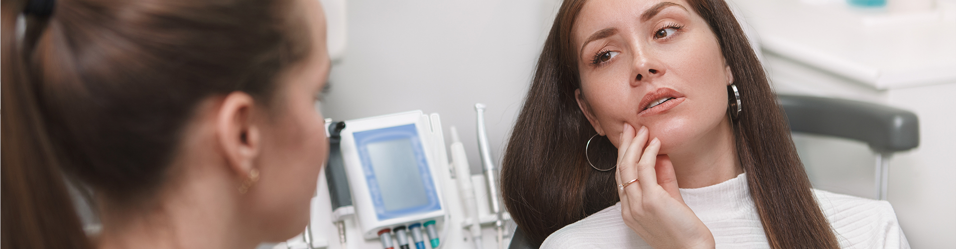 child holding cheek in dental chair with dentist