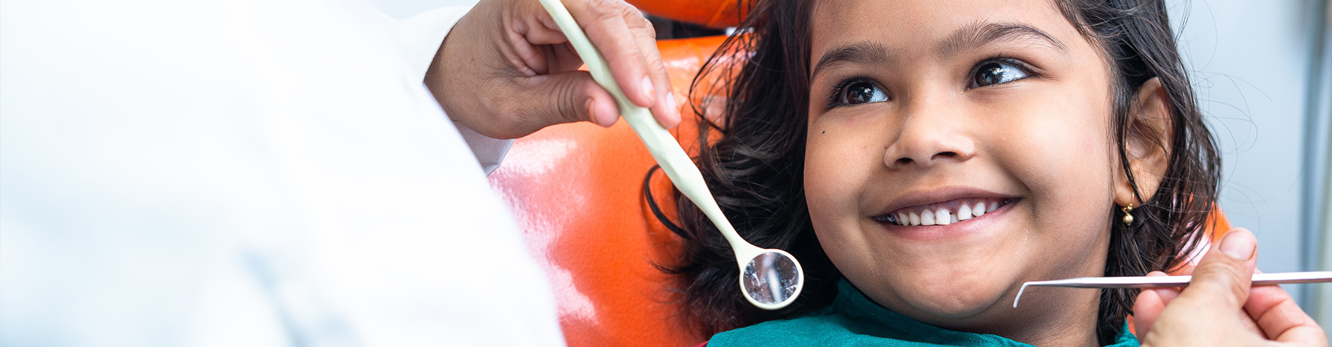 dentist holding dental tools by mouth of smiling girl