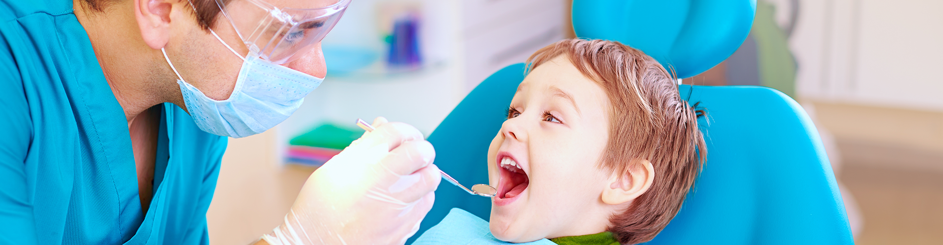 dentist placing dental mirror into boy's mouth