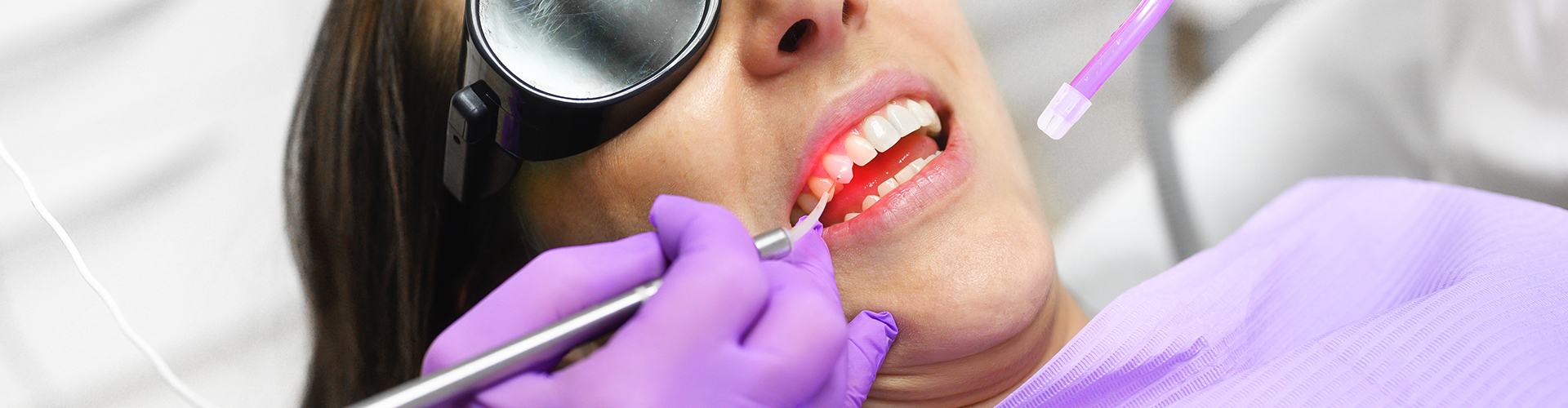 female in dental chair having laser teeth cleaning
