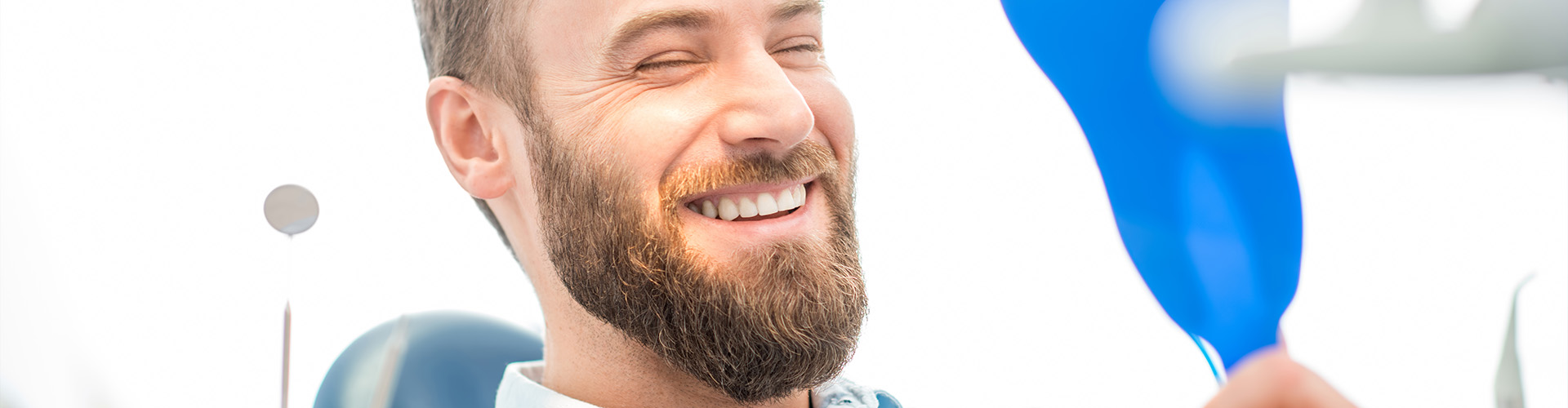 man smiling into hand mirror