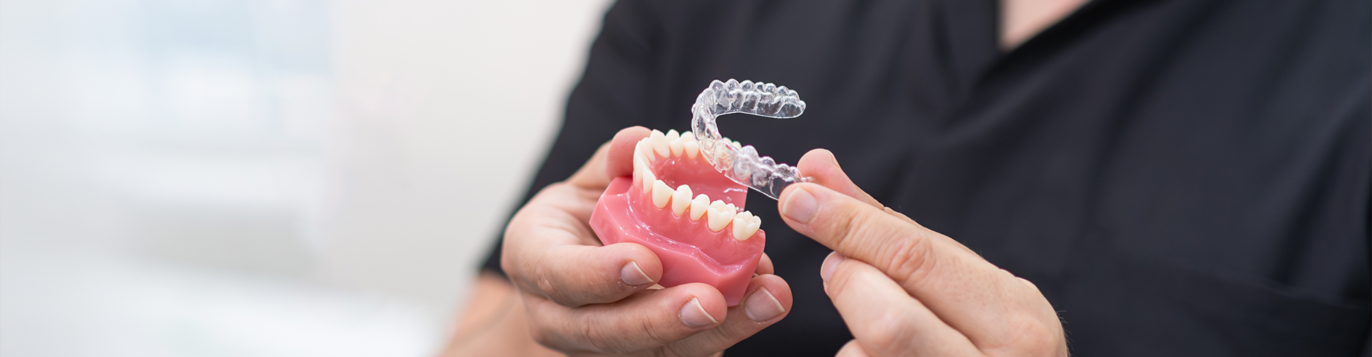 man holding jaw model and clear aligner in his hands